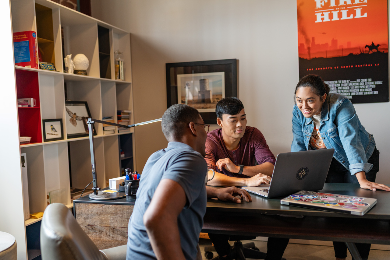 Three people smiling and collaborating