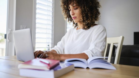 A young woman studying with a laptop computer in a home.