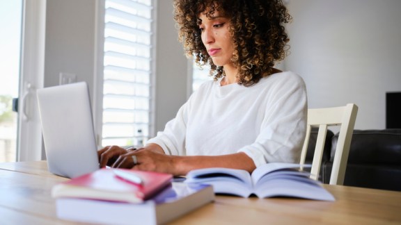 A young woman studying with a laptop computer in a home.