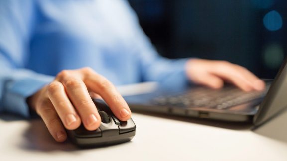 business, education, people and technology concept - close up of female hand with laptop and computer mouse on table