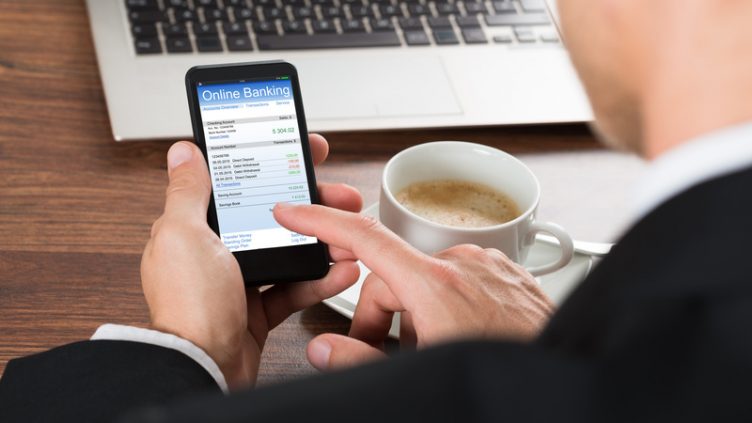 Close-up Of A Businessman Using Online Banking Service On Cellphone While Having Coffee