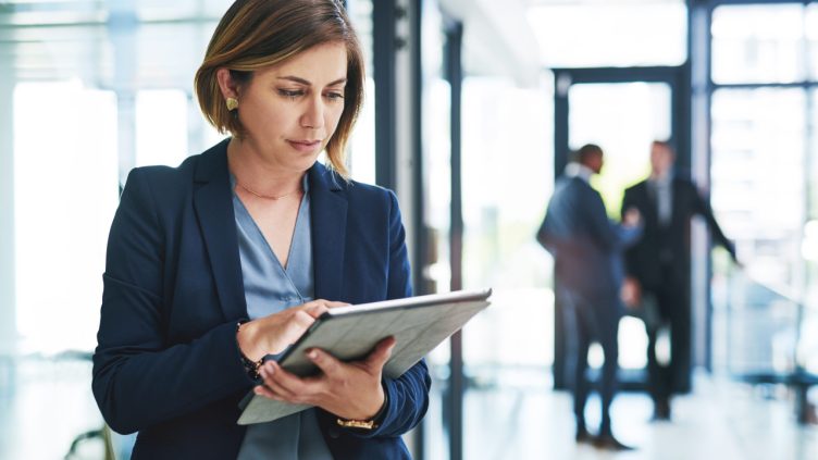 businesswoman using a digital tablet in an office with her colleagues in the background