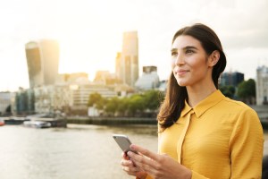 Woman looking up with mobile phone, sunset