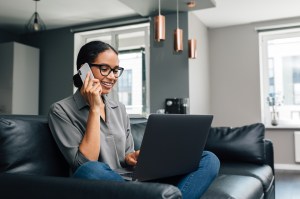 Smiling Woman Talking Over Mobile Phone While Sitting On Sofa