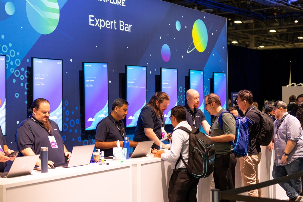 Wide shot of VMware Explore attendees collaborating with experts at the Expert Bar in The Hub.