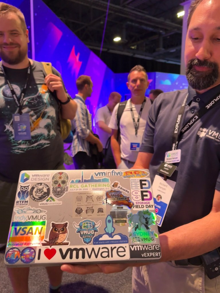 vExpert gathering in the Community Lounge at VMware Explore featuring laptop stickers