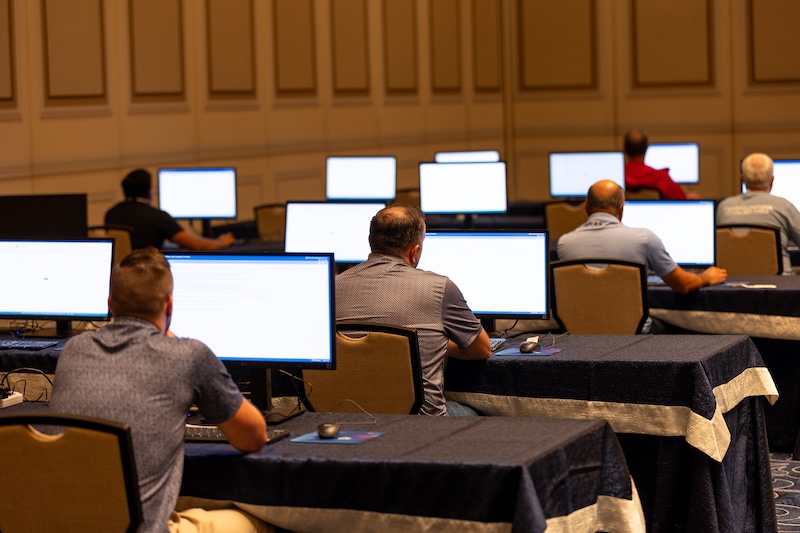 Attendees at monitors in the certification exam center at VMware Explore
