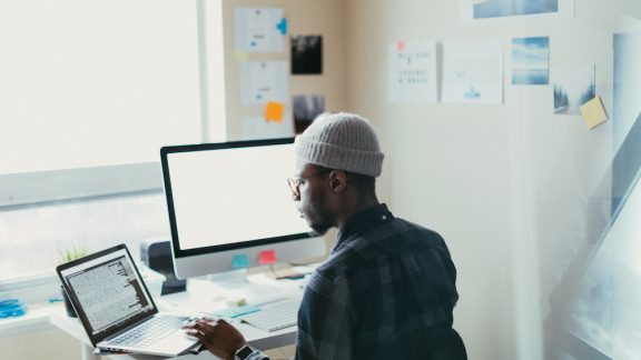 Man in his 20s working at his desk on his computer.