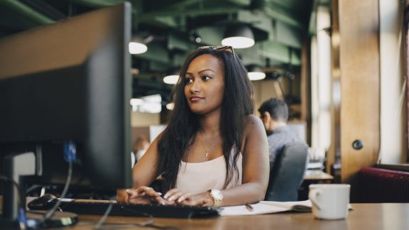 Young businesswoman using computer at desk in creative office