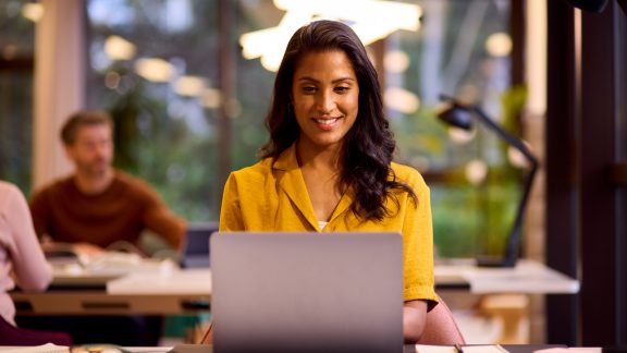 Mature Businesswoman Working On Laptop At Desk In Office