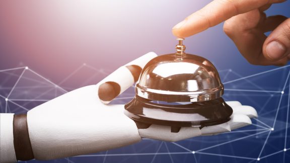 Close-up Of A Person Ringing Service Bell Hold By Robot Against Technology Background