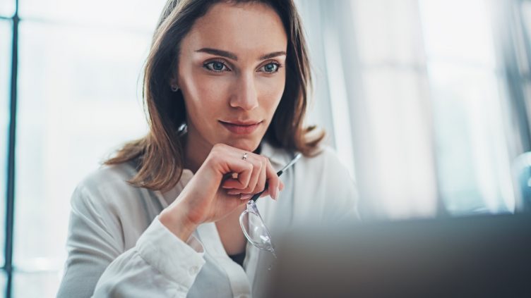 Confident business female using mobile laptop for looking a new business solution during work process at office.Blurred background