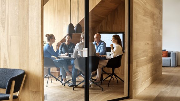 Business professionals discussing in meeting seen through glass door at office