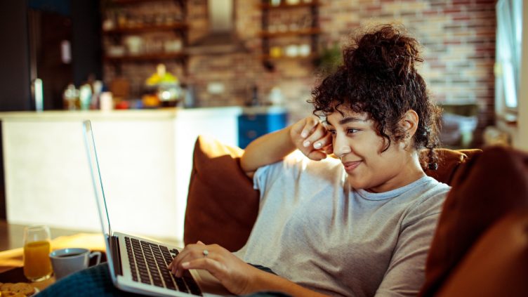 Close up of a young woman using a laptop at home