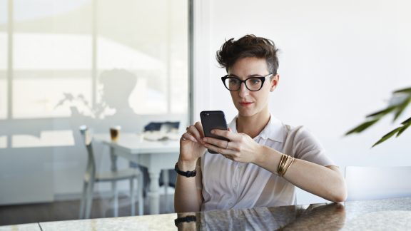 Cool businesswoman scrolling on phone in meeting room