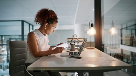 Shot of a young businesswoman using a digital tablet during a late night at work