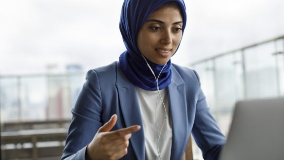 Young woman with headphones working on laptop