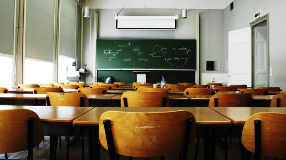 A large, empty classroom, lit by morning light.