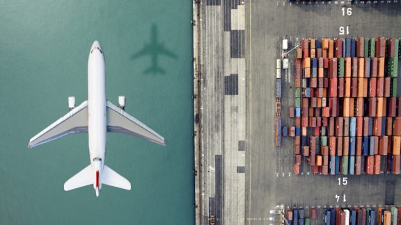 Airplane flying over container port