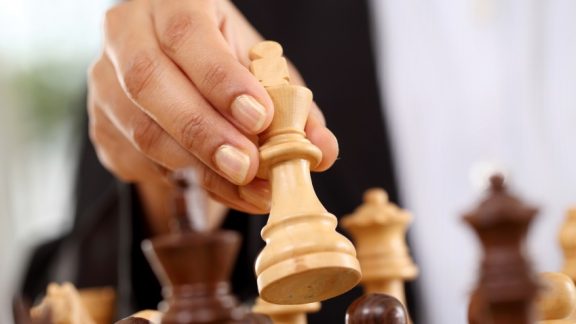 Closeup of business woman hand holding chess king piece