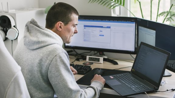 Young man using a laptop and computer at home