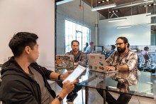 Three engineers at table, two on PCs and one on tablet