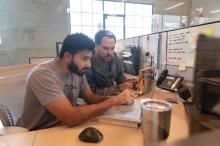 Two VDI administrators using laptops and looking at specific issue on one screen