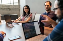 Three VMware IT personnel in conference room with laptops discussing vSphere CNS on vSAN