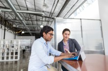 Two VMware workers looking at laptop in contemporary office
