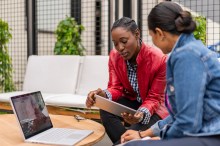 Two women with laptops in lobby