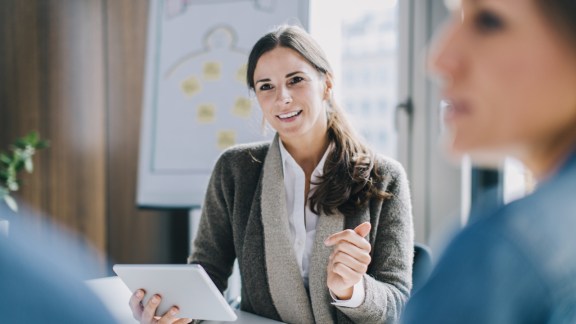 Businesswoman working with tablet while coaching a couple.