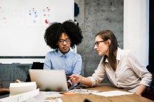 Two young women having a discussion with laptop
