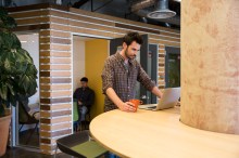 Standing man with coffee cup looking at laptop