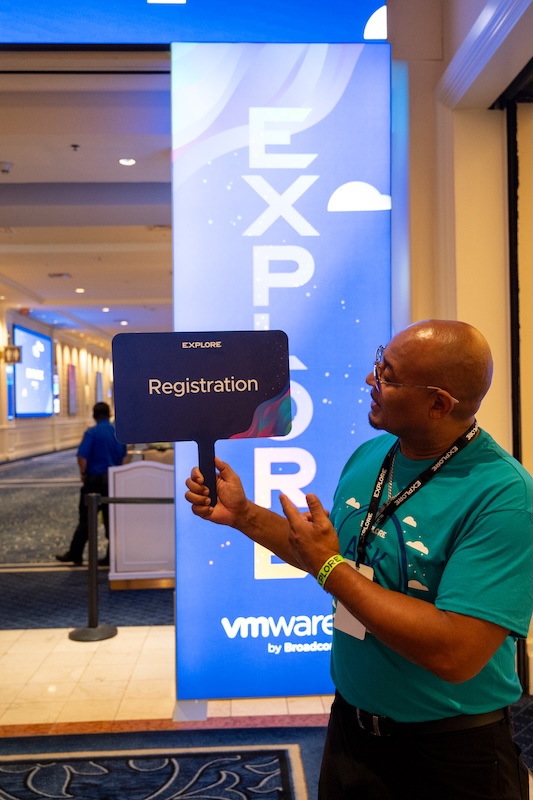 Brand ambassador with Registration paddle outside of the main entry at VMware Explore 2025 in Las Vegas